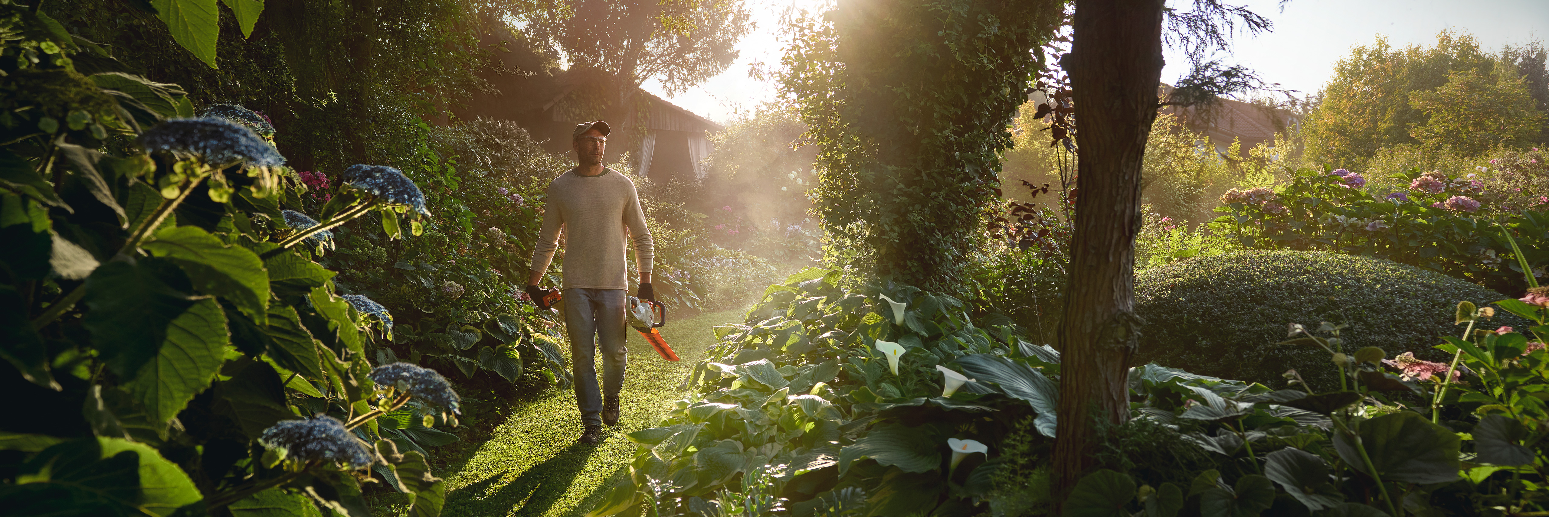 Un bărbat pe alee  în grădina privată, folosind produse cu acumulator STIHL AK