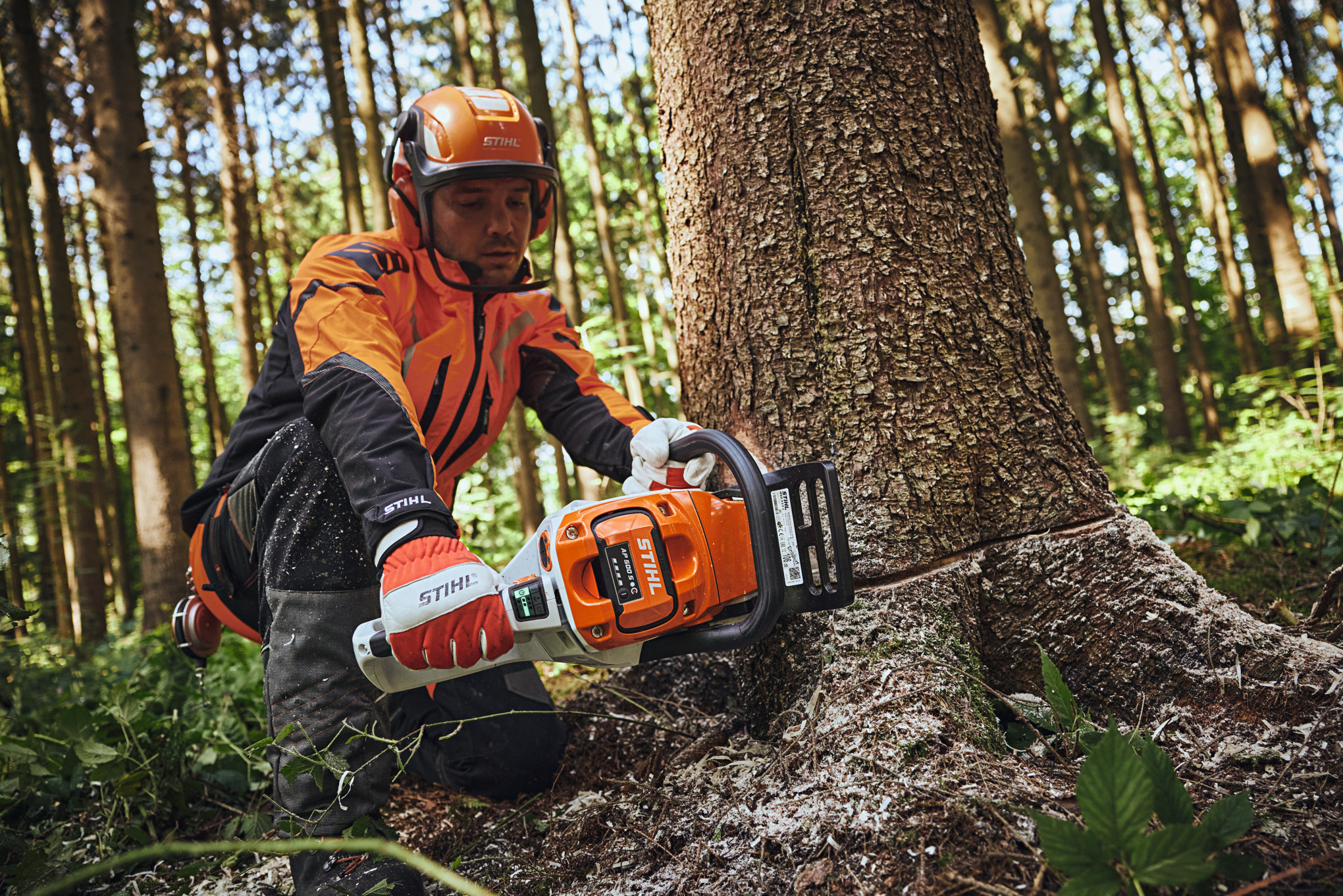 Un bărbat în echipament de protecție STIHL taie un butuc