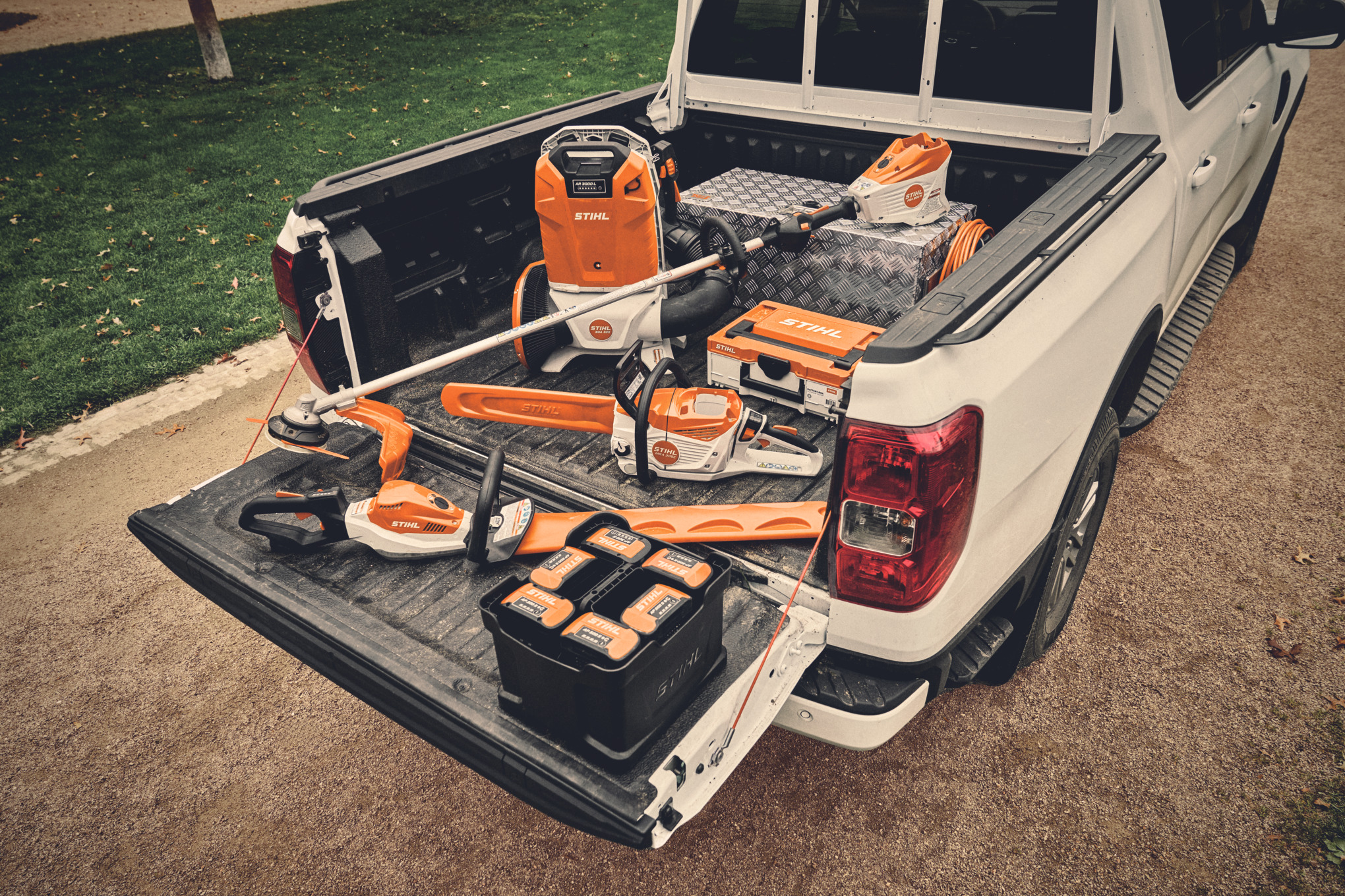 Diverse utilaje și acumulatorii corespunzători din sistemul STIHL AP, așezaţi pe platforma de încărcare a unui vehicul  