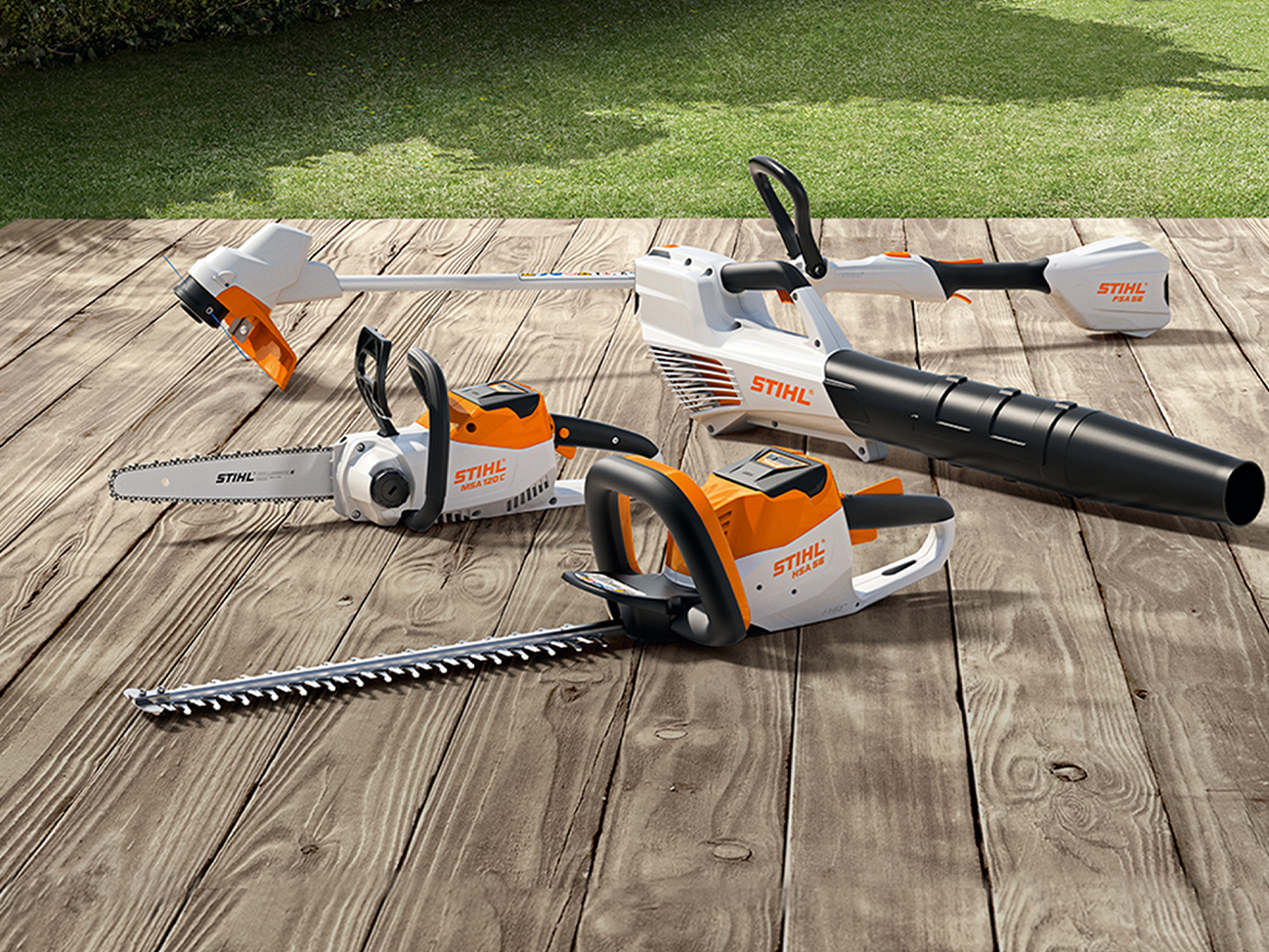 Motoferăstrău cu acumulator MSA 120 C, trimmer pentru gazon cu acumulator FSA 57, foarfecă de tuns garduri vii cu acumulator HSA 56, suflantă cu acumulator BGA 56 de la STIHL pe o terasă de lemn