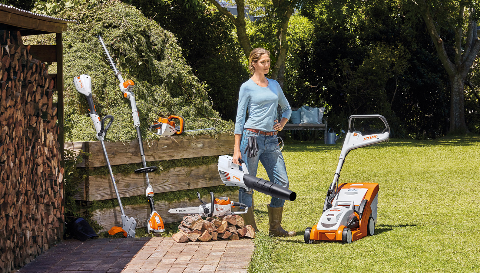 O femeie stă în grădină cu o selecție de produse cu acumulator de la STIHL