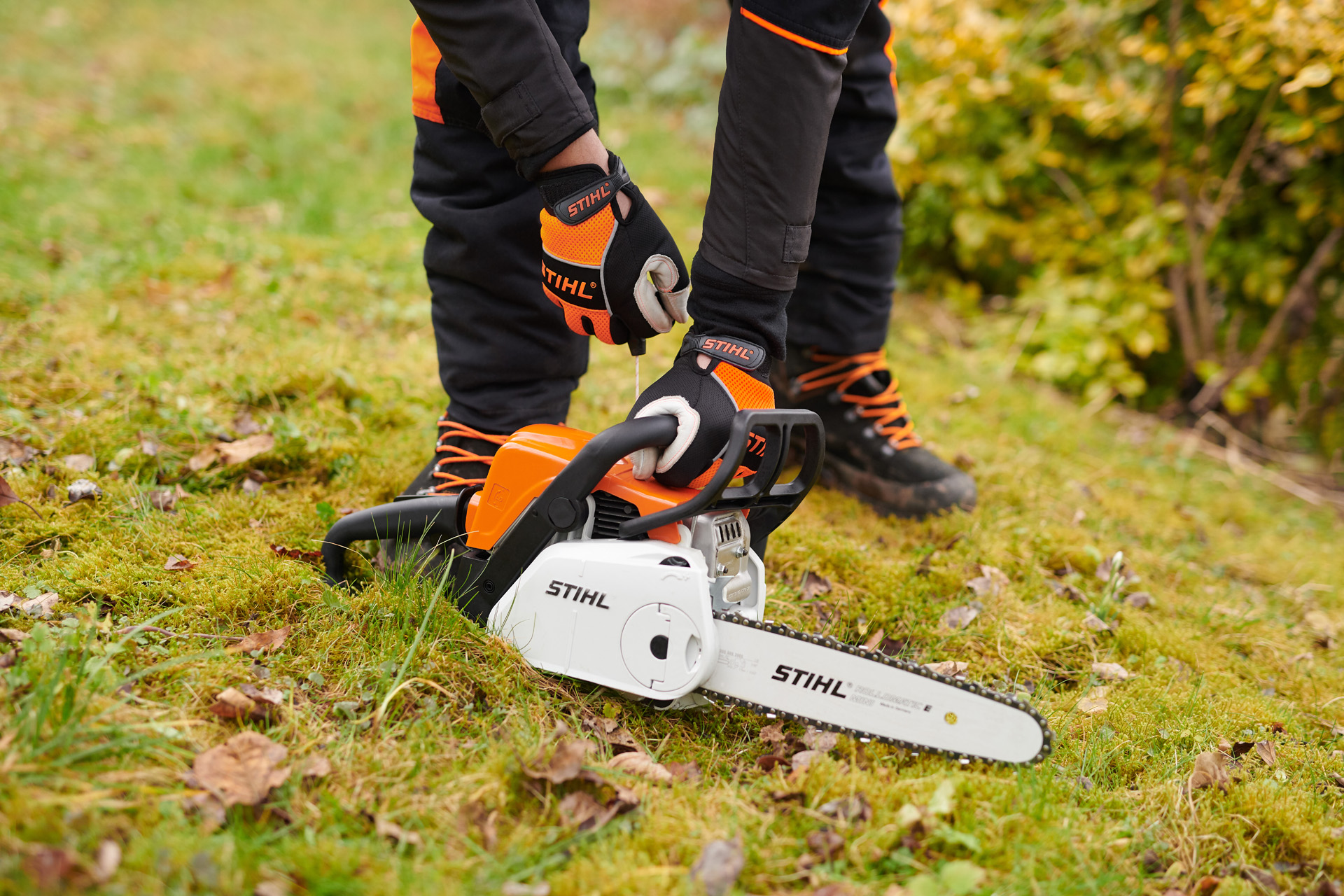 Un motoferăstrău pe benzină STIHL MS 180 C-BE cu ErgoStart pe iarbă, în curs de pornire
