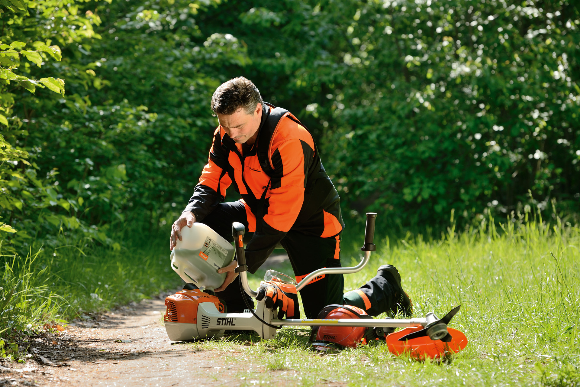 Un bărbat alimentează motocoasa STIHL cu un amestec ulei-benzină