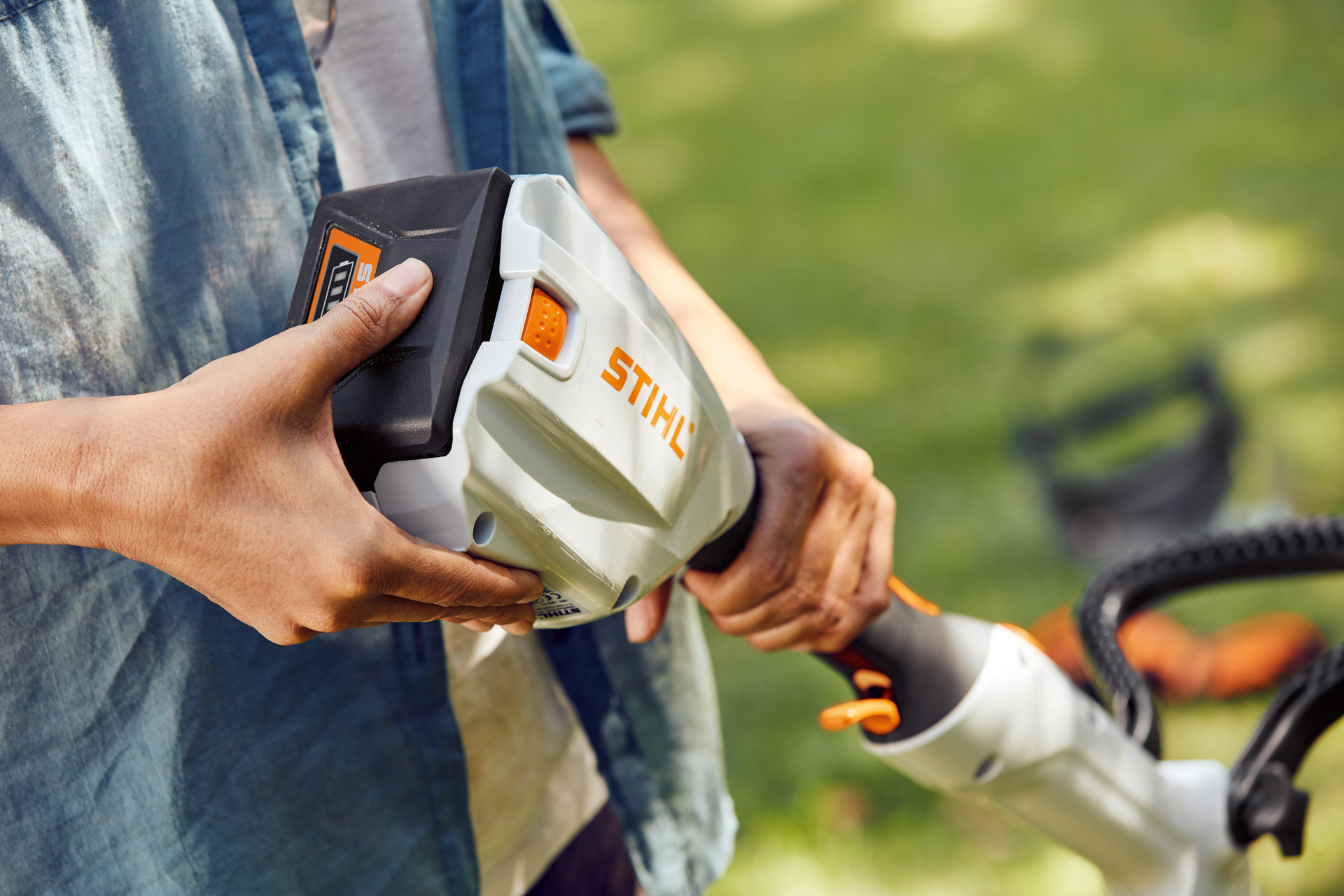 O persoană ține în mână motocoasa cu acumulator STIHL FSA 56 și ține mâna peste acumulator.