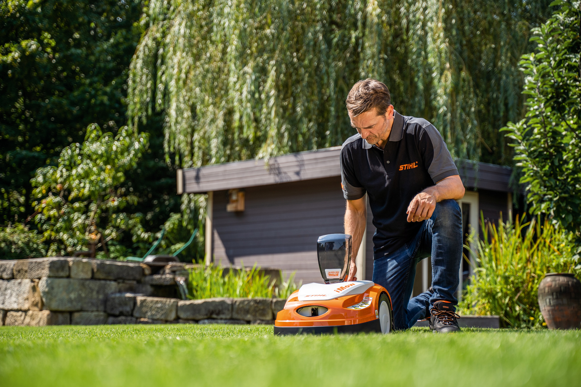 Un distribuitor STIHL programează planul de tundere a ierbii al unui robot de tuns iarba STIHL iMOW într-o grădină