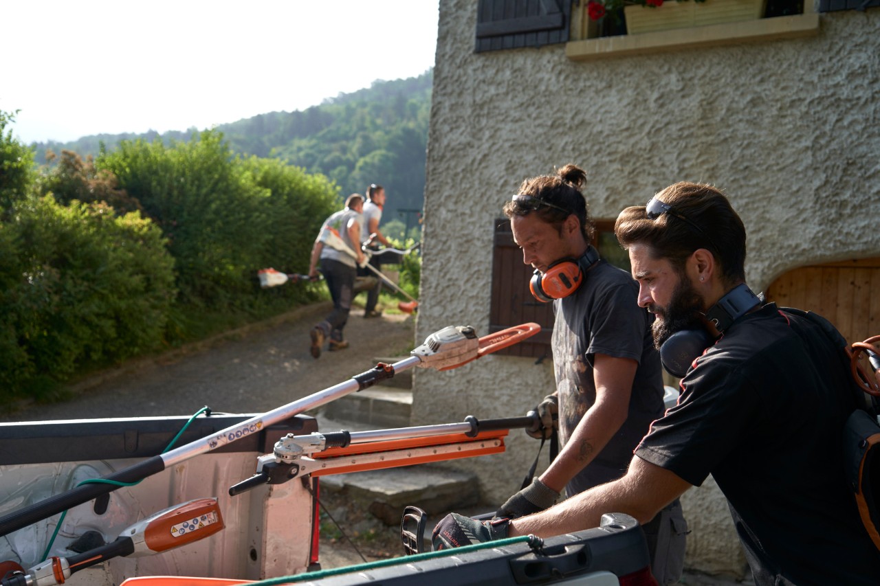 Julien Loquarelli, peisagist, descarcă echipamentul STIHL din vehicul împreună cu colegii săi.