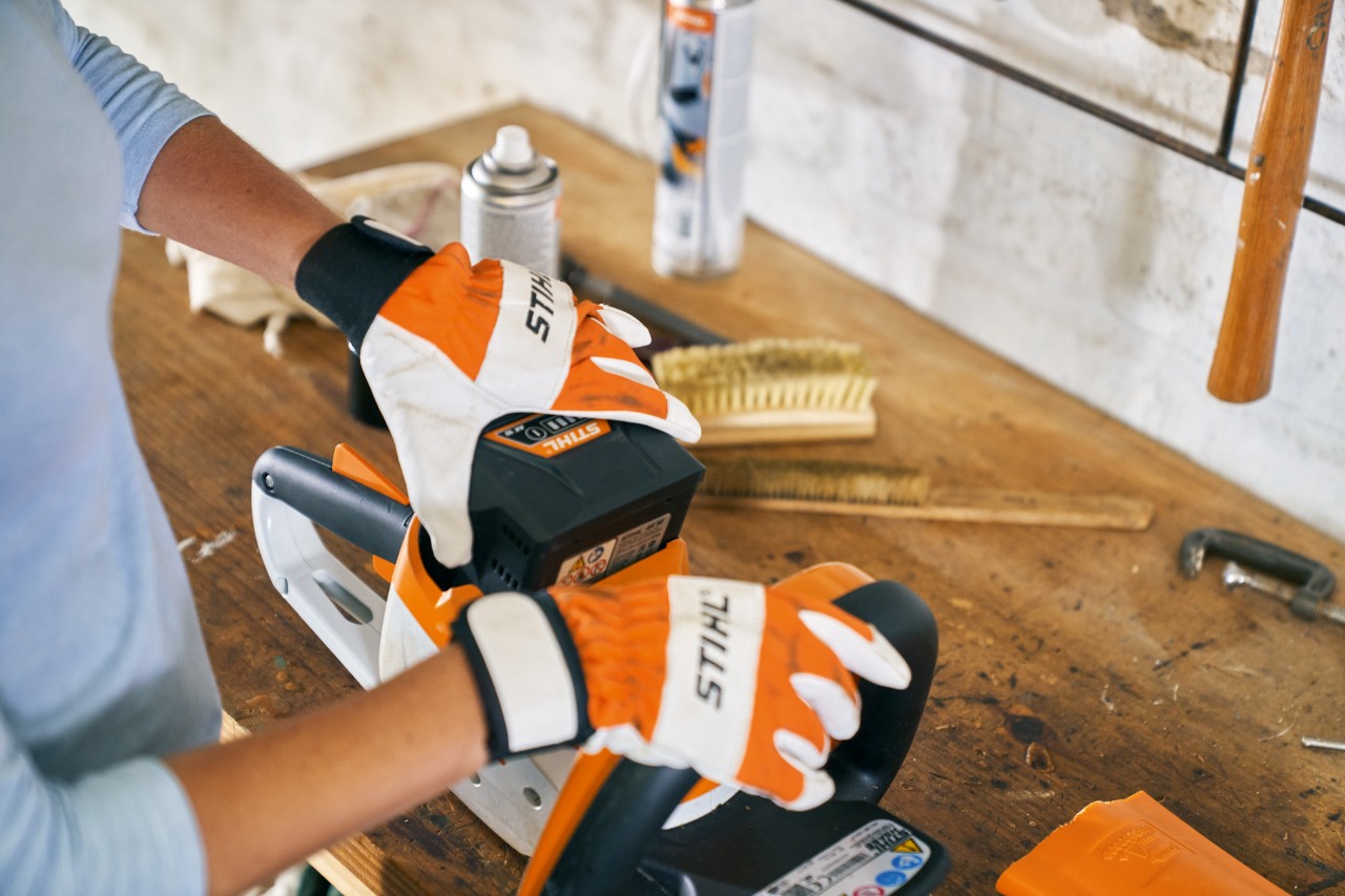 O persoană lucrând cu mănuși la foarfeca de tuns garduri vii cu acumulator STIHL HSA 56 