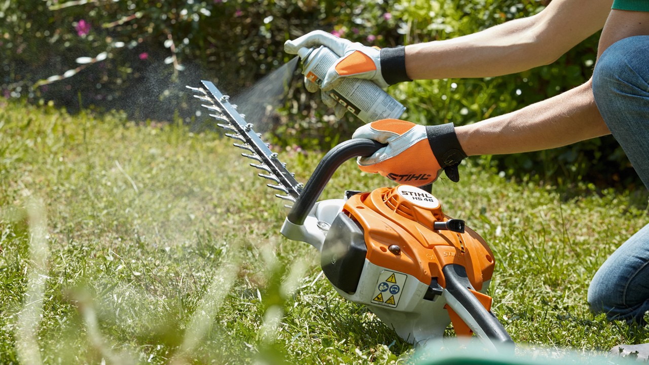Foarfeca de tuns garduri vii pe benzină STIHL HS 82 T pulverizată pe un gazon verde pentru a o curăța