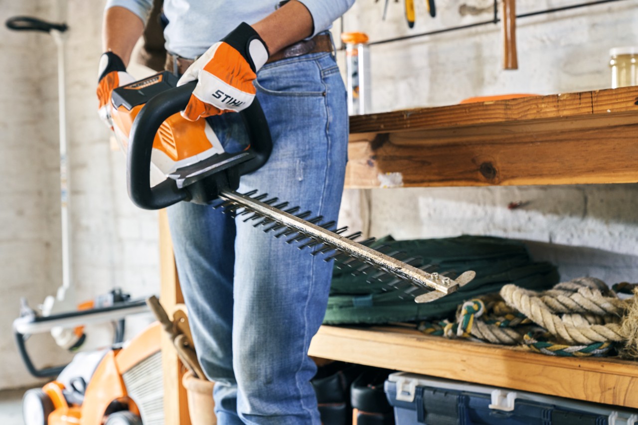 O femeie ține în mâini o foarfecă de tuns garduri vii cu acumulator STIHL HSA 56